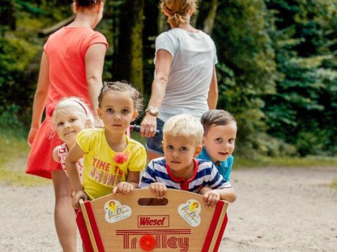 Ein Paar zieht einen Bollerwagen mit 4 Kindern hinter sich her